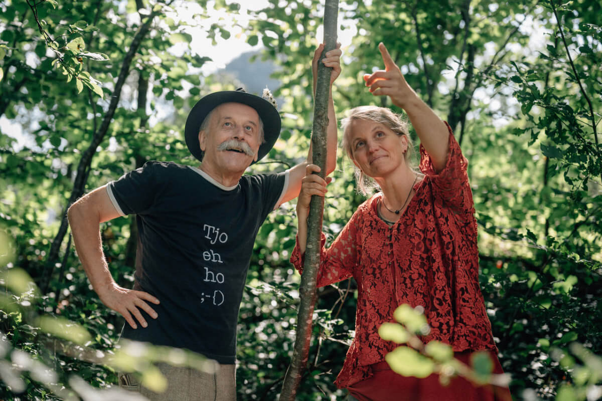 Helmut Wittmann und Momo heiß stehen im Wald gestützt auf einen langen Stock und schauen ins Blätterdach. Foto von Thom Trauner.